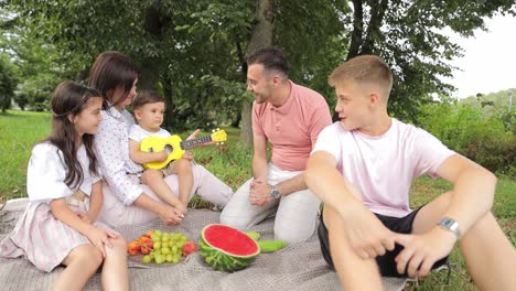 a happy family enjoys a picnic in a park with fruit