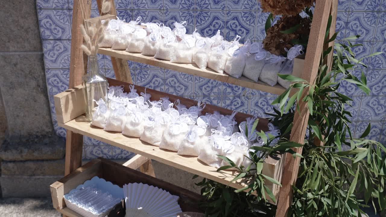 Small wedding rice bags tied with white ribbons arranged on a wooden shelf