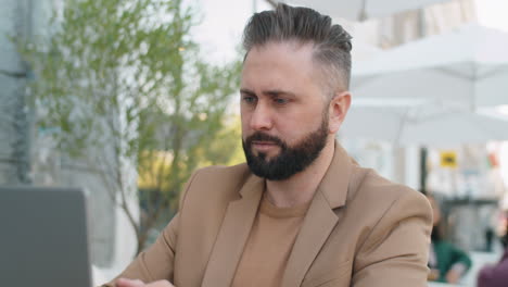caucasian businessman working on laptop in outdoor cafe