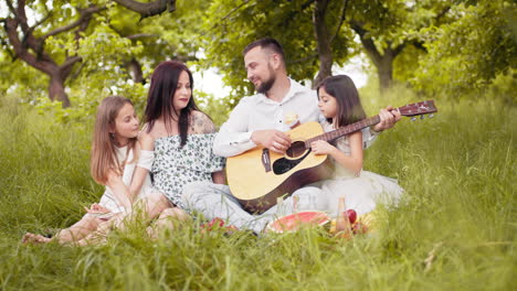 familia feliz tocando la guitarra en un picnic en el parque