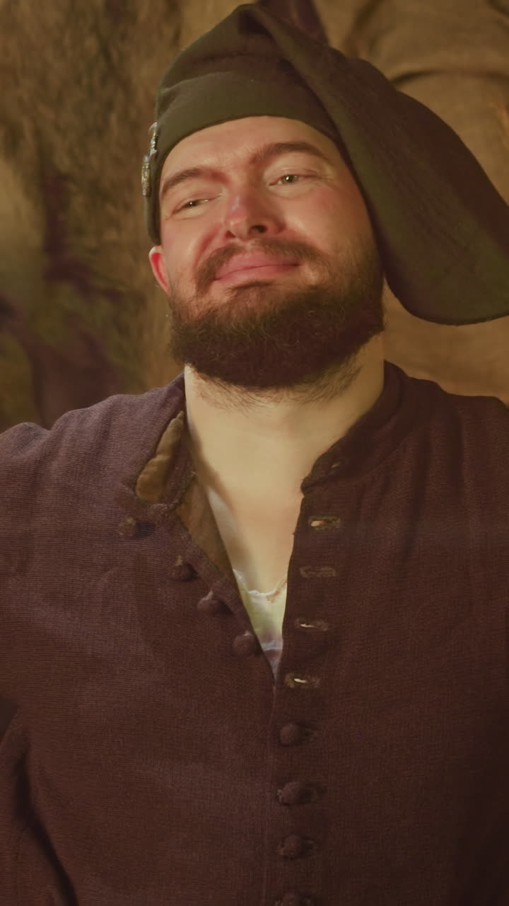 el astuto camarero sonríe al conocer a los invitados en la taberna. el empleado del bar medieval está feliz de servir a los viajeros en el pub. el carismático hombre barbudo con sombrero en el mostrador