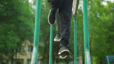 primer plano de dos personas colgando de equipos al aire libre, moviendo sus piernas en un movimiento sincronizado como si estuvieran montando una bicicleta