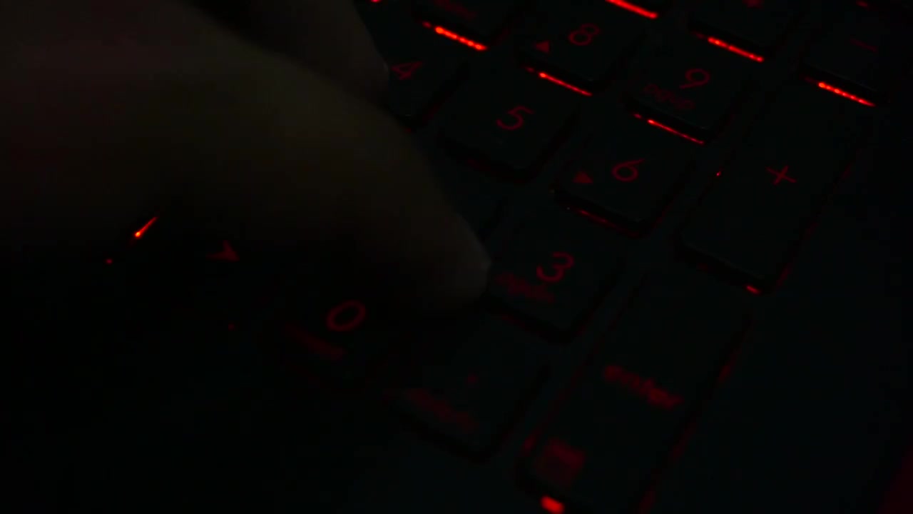 Close up of fingers typing on a lighted laptop keyboard number