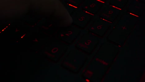 primer plano de los dedos escribiendo en un número de teclado portátil iluminado