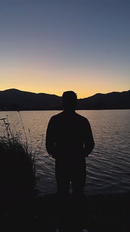 man silhouetted at sunset on a lake