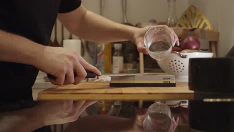 chef puts water onto a sharping stone on the kitchen table