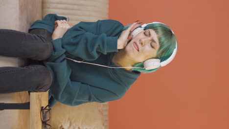 Vertical-video-of-Young-woman-listening-to-music-with-headphones-is-unhappy-and-sad.