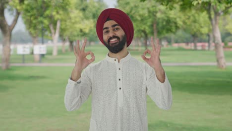 happy sikh indian man showing okay sign in park