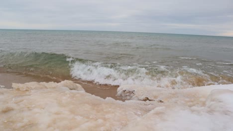 las olas rompen a lo largo de las orillas heladas del lago michigan en un día ventoso en manistee
