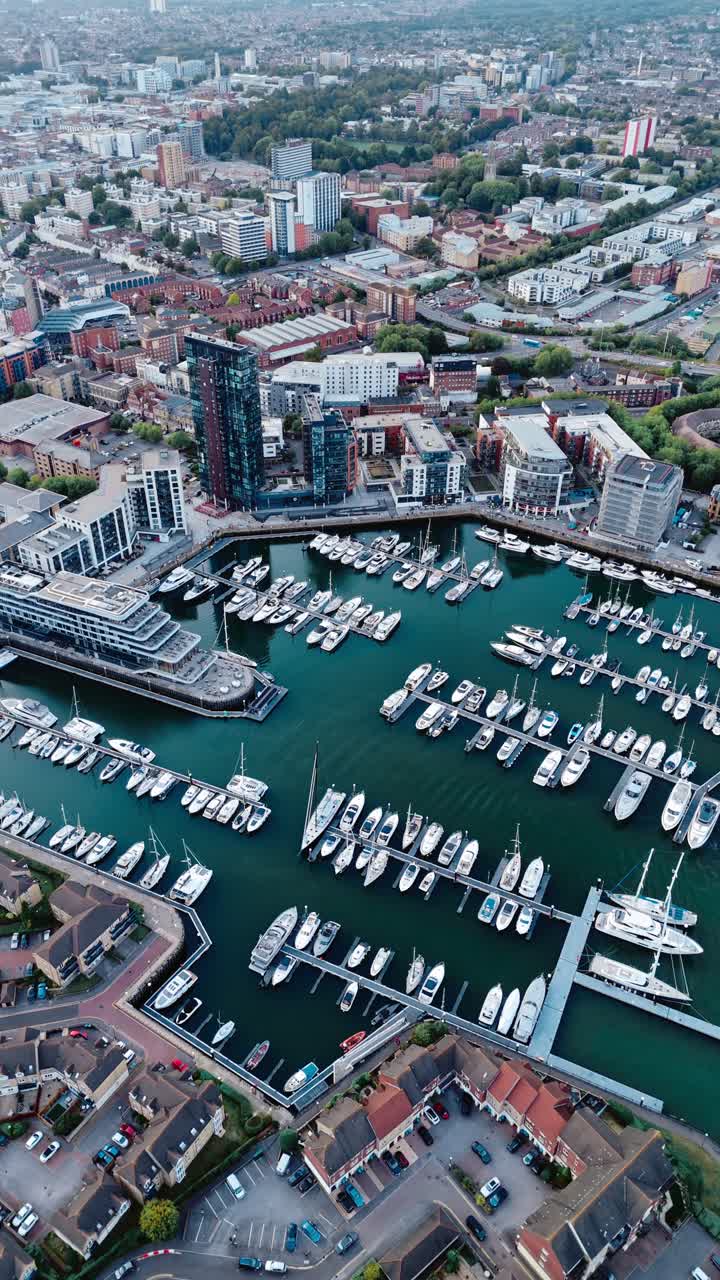 Aerial drone footage of Ocean Village marina in Southampton, showcasing boats, docks, buildings, and waterfront real estate under soft daylight at sunset shot during autumn
