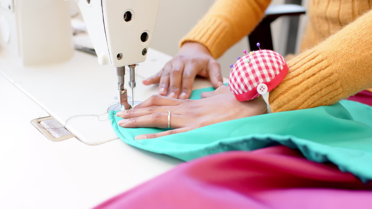 diseñadora de moda biracial cosida de tela con máquina de coser en el estudio, cámara lenta
