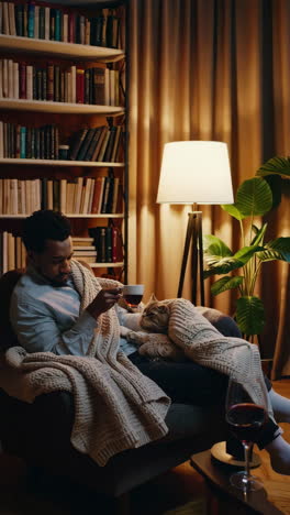 man and cat relaxing with tea in a cozy home environment
