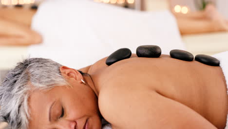 senior woman in spa for hot stone massage