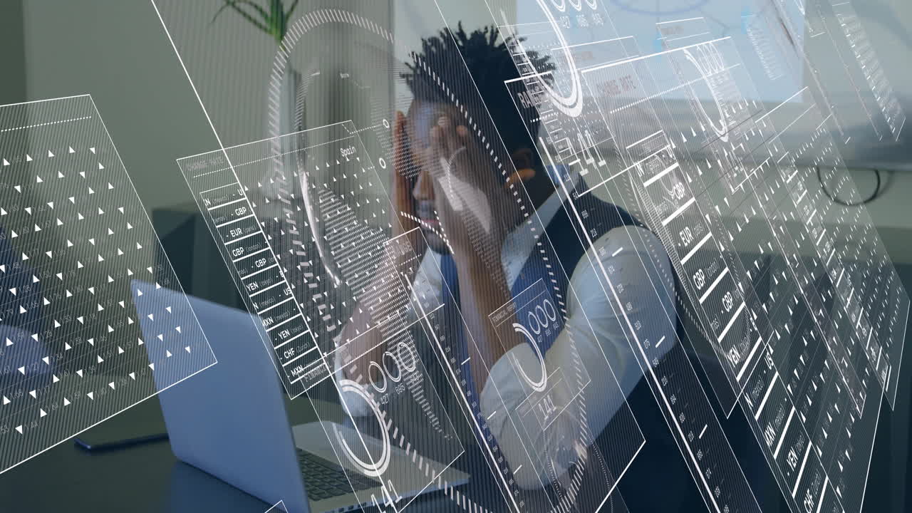 Man pressing temples, leaning over laptop, viewing animated finance graphs and data overlays