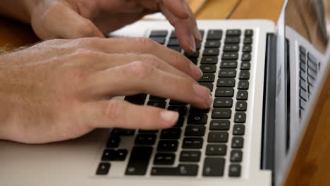 vista de cerca de las manos masculinas escribiendo en una computadora portátil