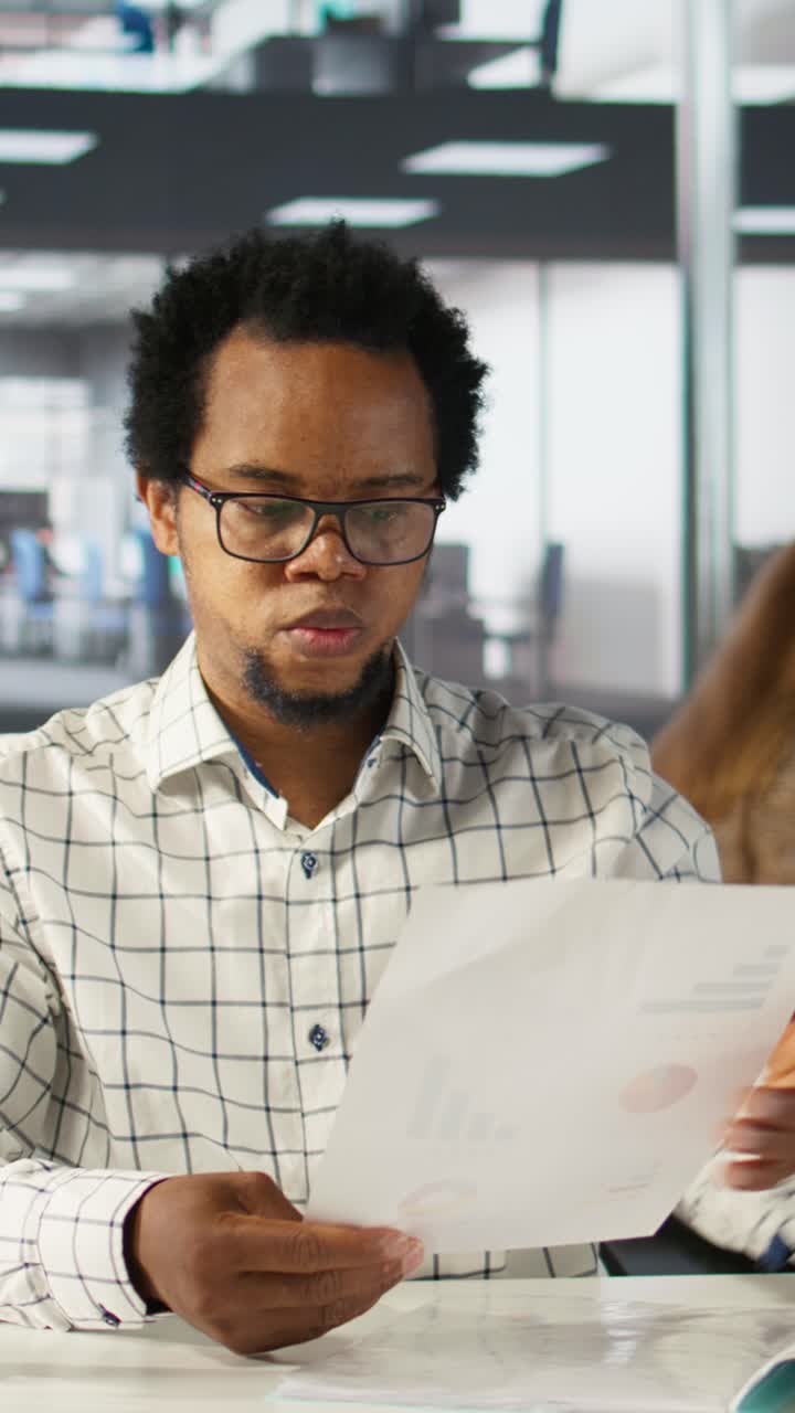 Empresário Afro-Americano Analisando Documentos com Gráficos no Escritório
