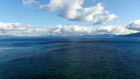 Fliegen-Sie-In-Geringer-Höhe-über-Dem-See-Mit-Blauem-Wasser-Und-Wolken