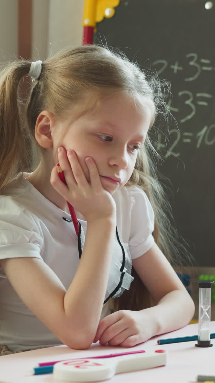Elder sister looks at little brother drawing figure with ruler in home classroom. Bored blonde girl helps toddler kid to learn shapes in children room