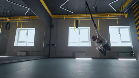 stretching training in modern gym with trx system young sportive lady is flying over floor