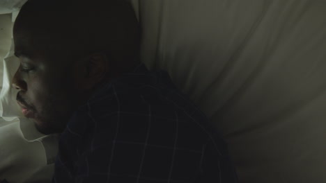 hombre de mediana edad acostado de lado en la cama mientras mira su teléfono