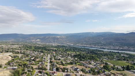 the wonderful village surrounded by green trees and houses in background with high mountains and a bright blue cloudy sky - aerial shot