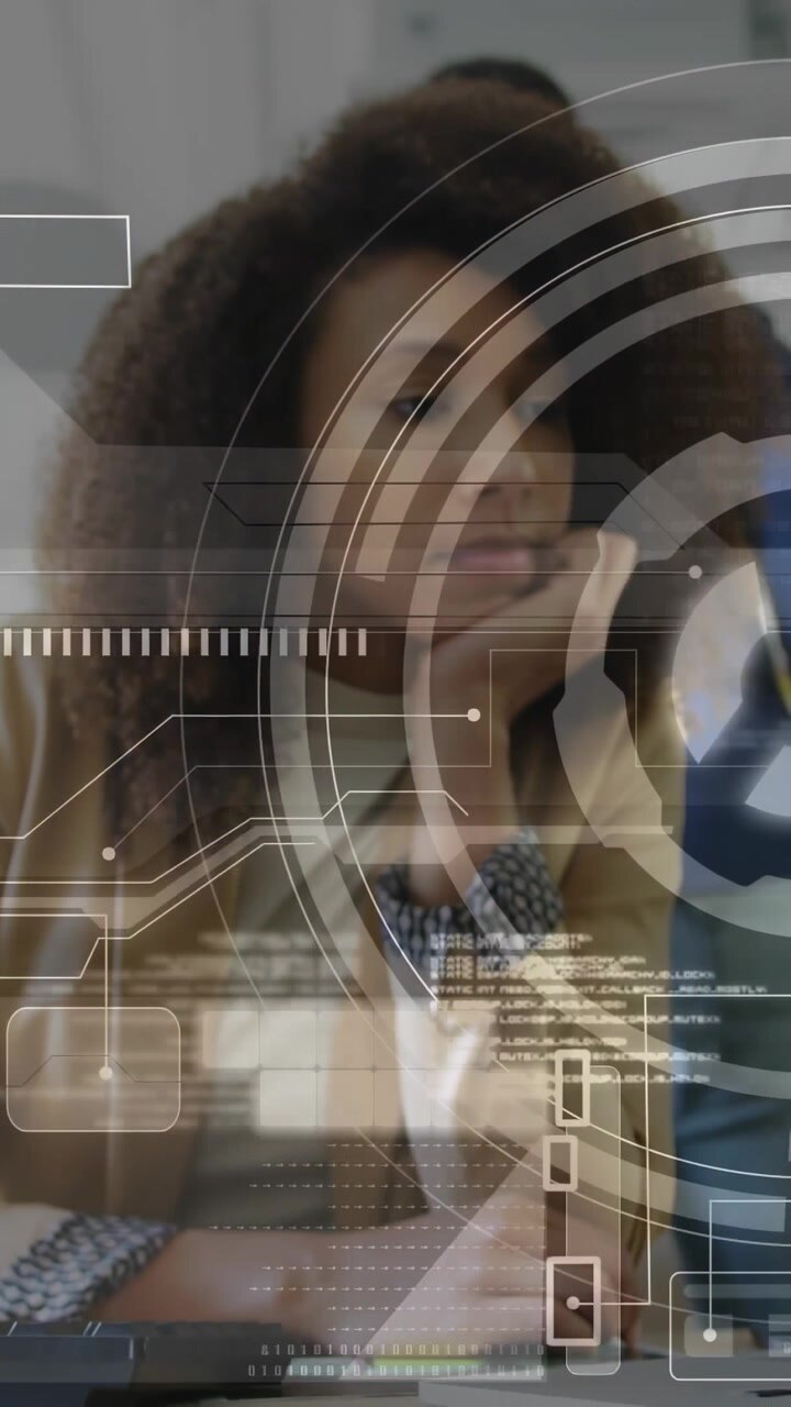 Vertical video: Woman at desk turning head right as coworker leaning in, tech HUD charts animating