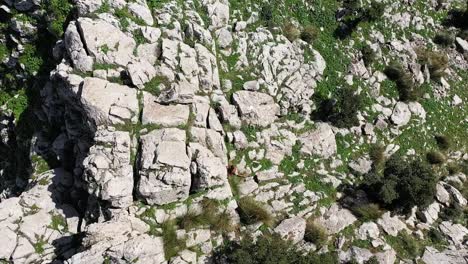 una toma giratoria de un dron de un hombre negro local caminando entre las rocas para subir a la cima de zaghouan en túnez durante un caluroso día de verano con luz solar intensa