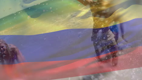 animación de la bandera colombiana sobre amigos caucásicos felices salpicando agua mientras disfrutan en el mar