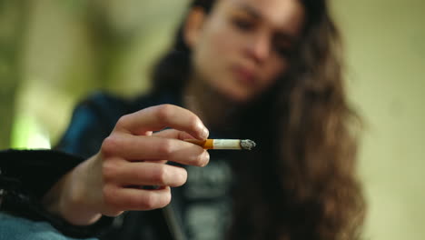 girl smoking cigarette looking at cigarette smoke