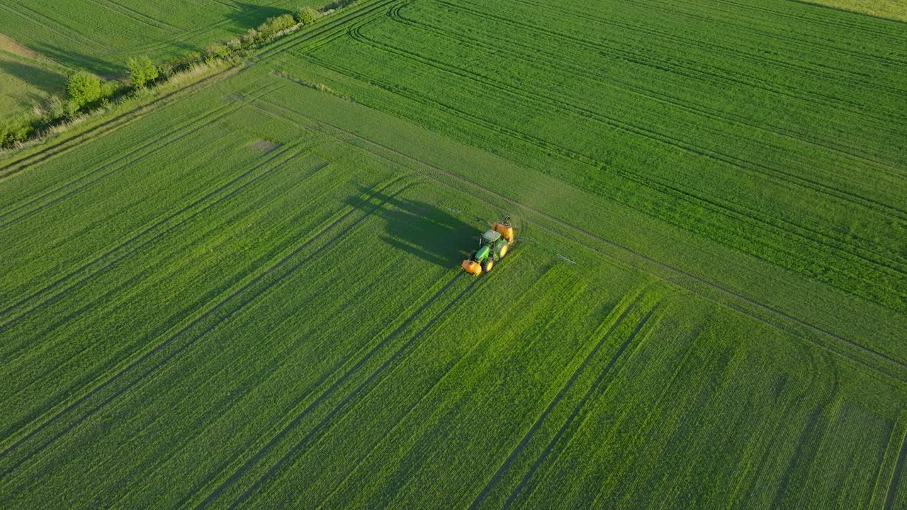 vista aérea de un agricultor rociando campos de cultivos con tractor, fumigación de pesticidas y fertilizantes, noche soleada de verano, luz de la hora dorada, tiro de dron de ojo de pájaro ancho