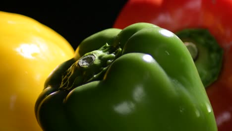 natural fresh peppers tricolour vegetables gyrating on black background