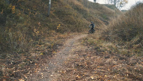 ciclista masculino con mochila y casco montando en bicicleta de montaña en medio del valle