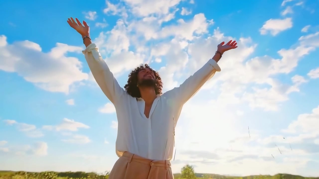 Homem Feliz Erguendo os Braços para o Céu em um Campo Ensolarado