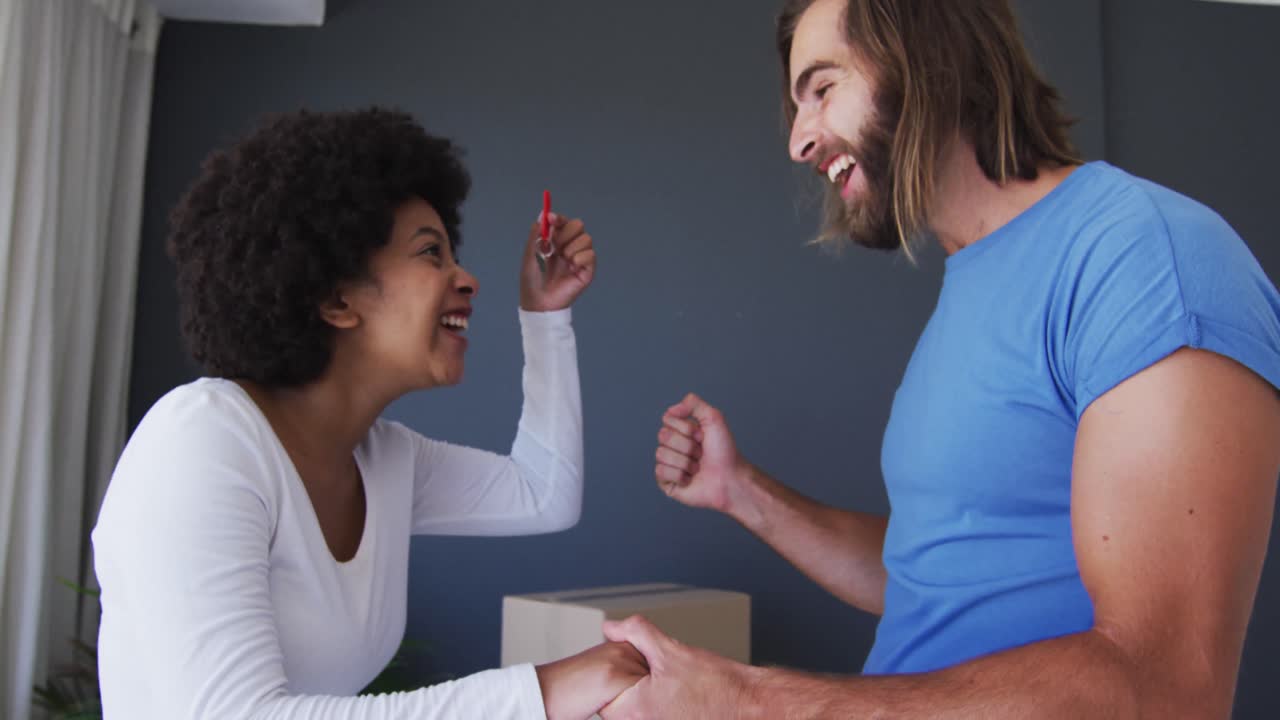 Happy mixed race couple holding house keys at new apartment house