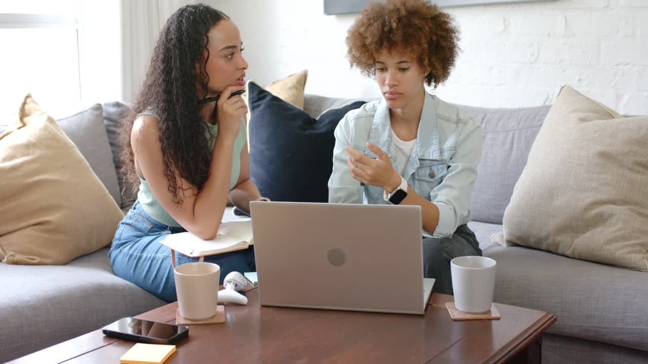Due donne afroamericane, la sinistra parla tenendo un quaderno e una penna, la destra digita su un laptop.