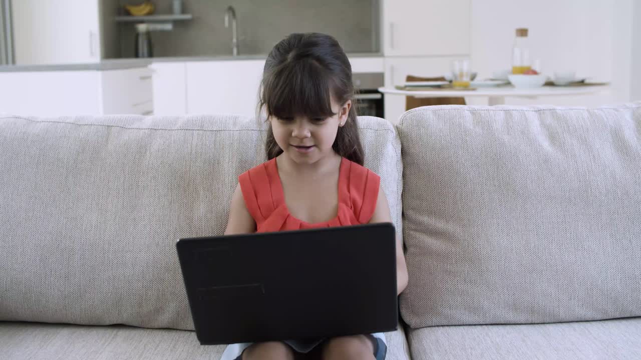 una niña alegre y emocionada usando una computadora portátil sola
