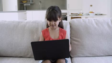 Excited-joyful-little-girl-using-laptop-by-herself