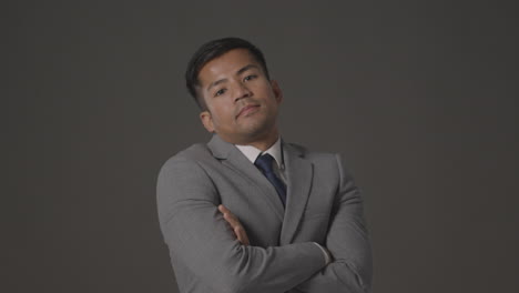 studio portrait of serious businessman in suit against grey background looking at camera 1