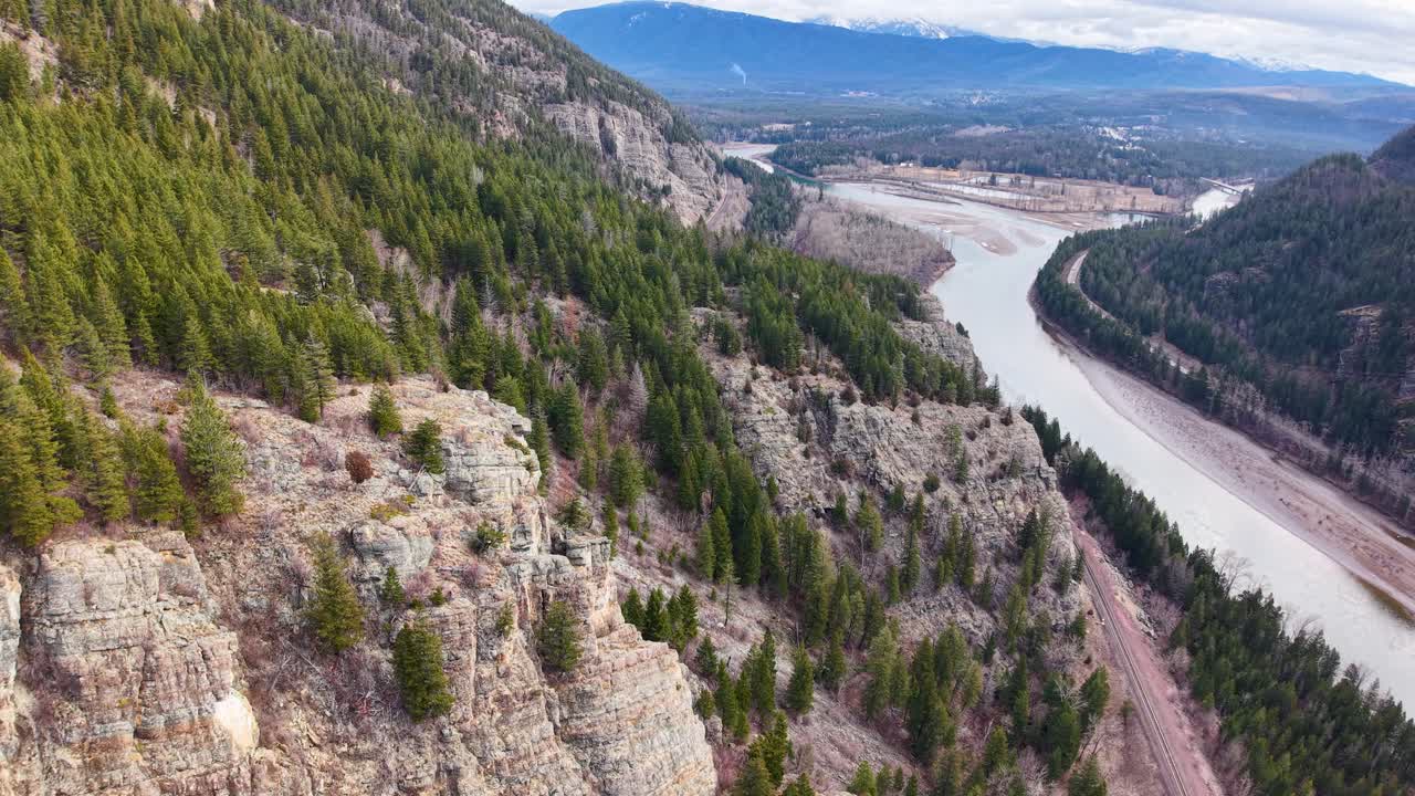 Luftfoto fra drone af den bugtende Flathead River, der løber gennem en skovklædt kløft med klippefyldte skrænter og en vej langs flodbredden nær Whitefish, Montana