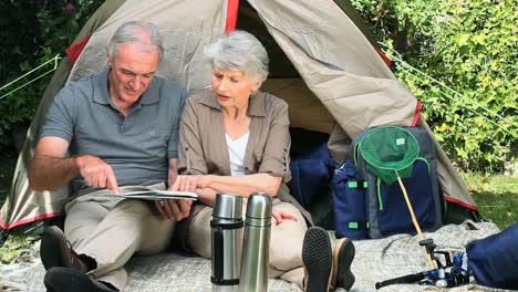 seniors looking at a map sitting front of a tent