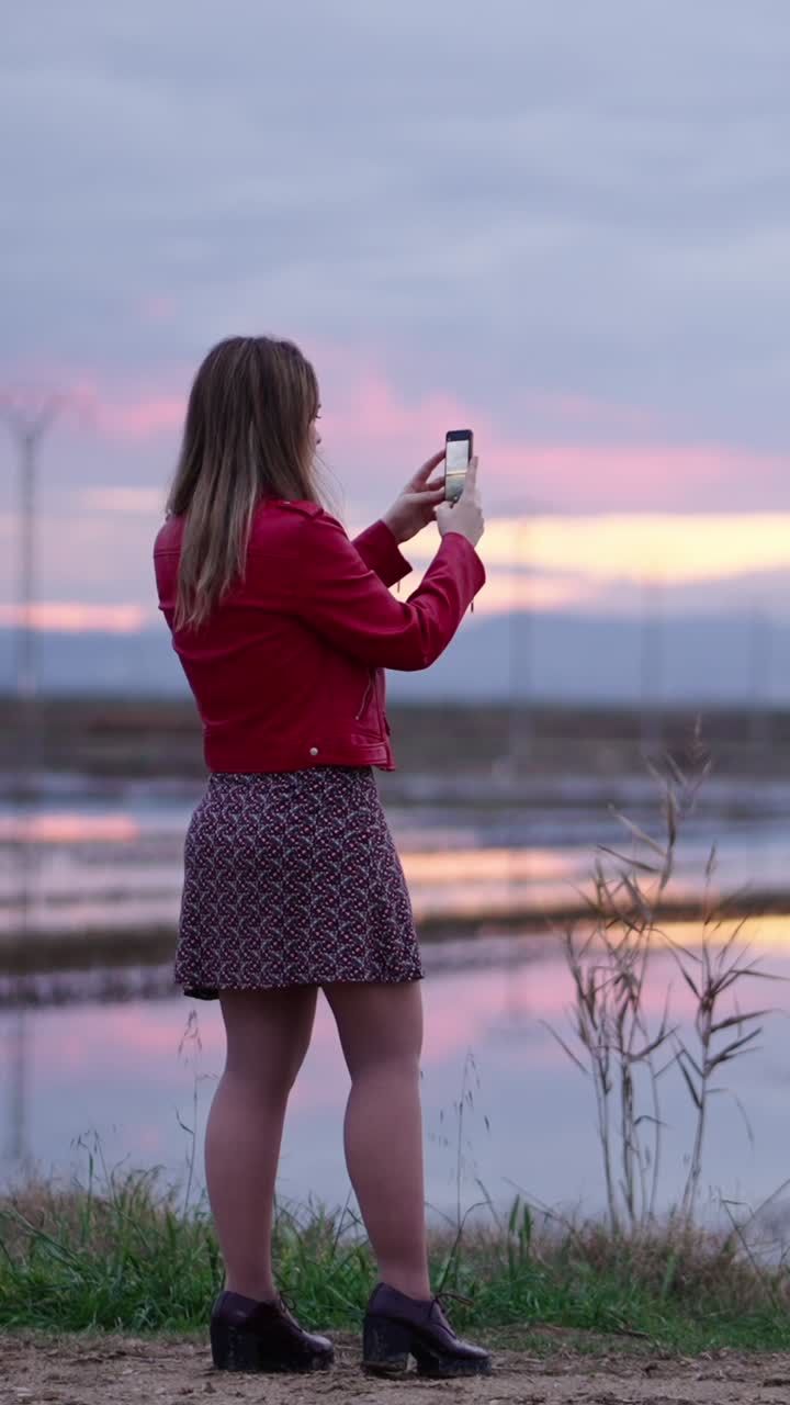 Woman taking pictures at sunset