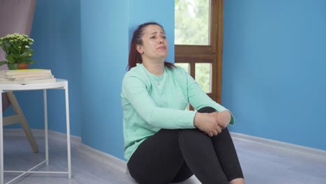 la mujer sentada en el suelo está llorando. desalentada.