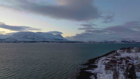 colorful polar night sky behind snowy mountains in norway, aerial view