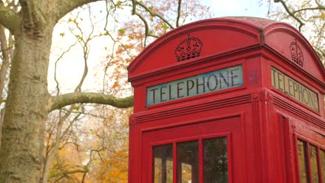 Old-Red-Telephone-Booth-In-Autumn-Urban-Park-In-London,-England,-United-Kingdom