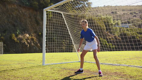 playing soccer, girl in goalkeeping position on school field, ready to defend