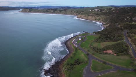 aerial view of a coastal bay with surfers and a parking lot