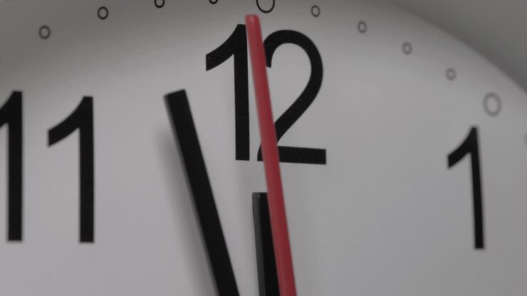 Close-up of a white clock face suggesting the passing of time. Round white clock with black Arabic numerals