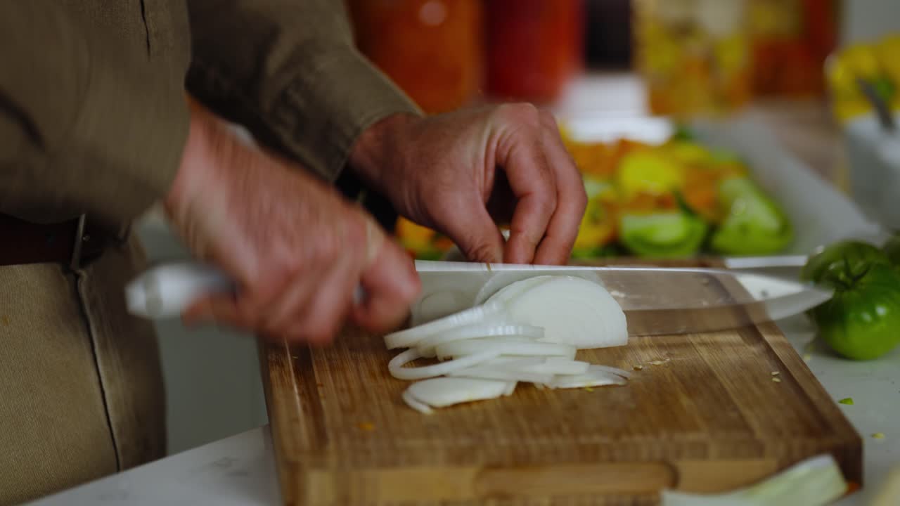 Closeup footage of cutting of white onions into halves by male chef inside kitchen.