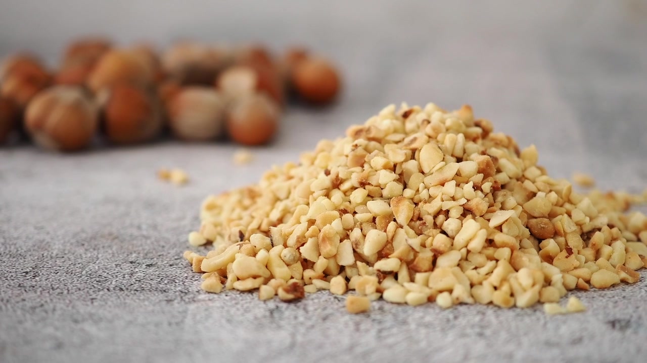 Mucchio di nocciole tritate con nocciole intere sullo sfondo