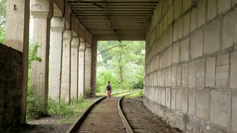 young girl walks on the reailway in the tunnel